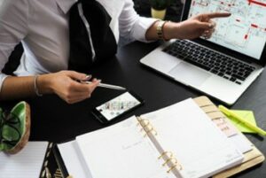 A woman in a white and black blouse pointing at property plans on a laptop.