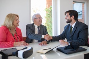 Men shaking hands while sitting at the table.